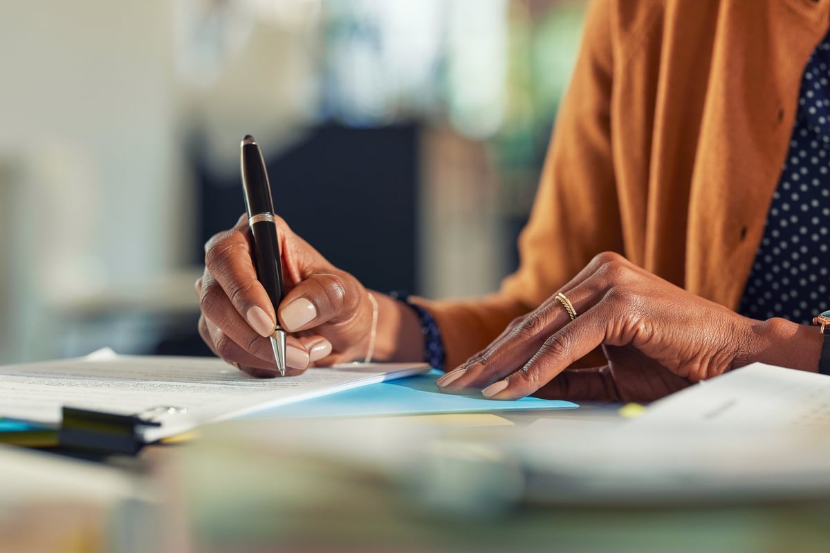 Close up of Black woman's hands signing legal document with pen